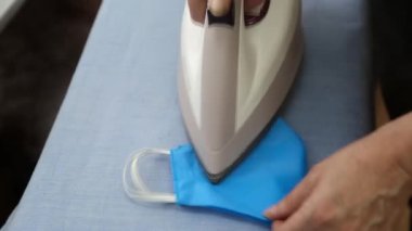 Yakın plan, yeniden kullanılabilir yüz maskesi yeniden kullanılması için buğulandı ve ütülendi. Sıcak buhar tedavisi, tıbbi maske dezenfeksiyonu. Coronavirüs salgını sırasında tıbbi maske eksikliği kavramı.