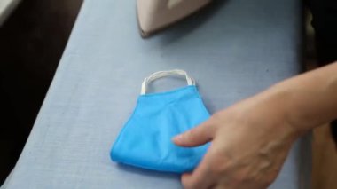 Yakın plan, yeniden kullanılabilir yüz maskesi yeniden kullanılması için buğulandı ve ütülendi. Sıcak buhar tedavisi, tıbbi maske dezenfeksiyonu. Coronavirüs salgını sırasında tıbbi maske eksikliği kavramı.