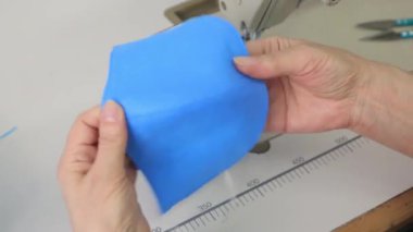 Yakın plan, bir kadın elinde yeni dikilmiş yüz maskesi tutuyor. Koronavirüs salgını sırasında tıbbi maske eksikliği kavramı.