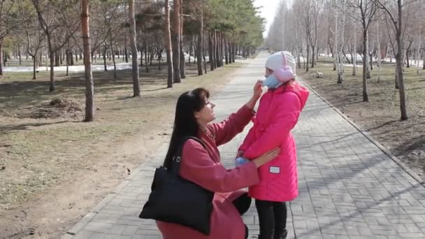 娘と一緒に若い母親は 医療マスクを削除します パンデミックの間の公園の散歩 — ストック動画