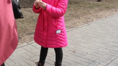 Pembe salam ceketli, şapkalı, kulaklıklı ve tıbbi maskeli genç bir kızın portresi. Koronavirüs salgını sırasında parkta yürüyüş..