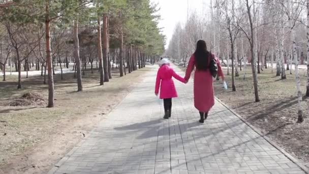母親と娘は医療マスクを手に公園を歩いています コロナウイルスのパンデミックの間の公園の散歩 — ストック動画