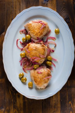 Kavrulmuş tavuk uyluk zeytin ve beyaz tahta üzerinde kırmızı soğan ile