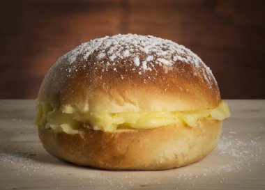 Ahşap zemin üzerine vanilya kremalı ekmek topu ve şeker tozu.