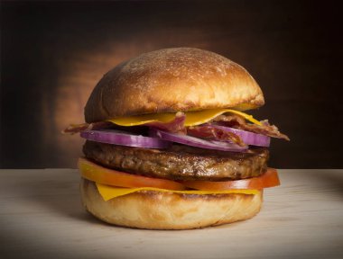 Çift peynirli burger ve rustik masada kırmızı soğan