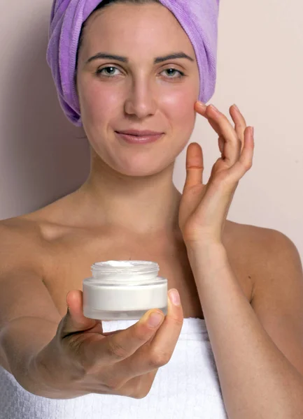 Foto Mujer Joven Toalla Púrpura Cabeza Sosteniendo Aplicar Crema Facial —  Fotos de Stock