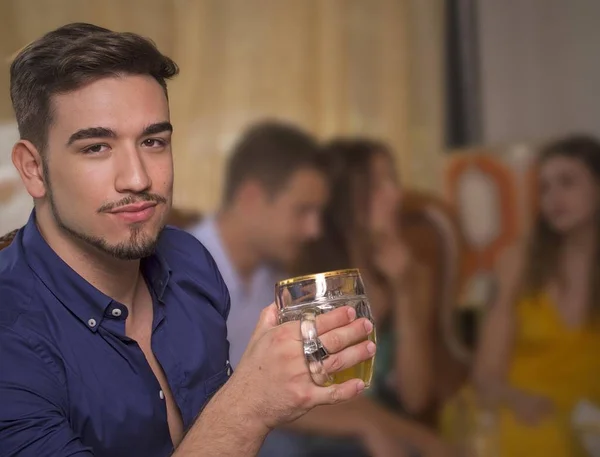 Young man drink beer in a vintage athmosphere pub restaurant bar and friend on blured background