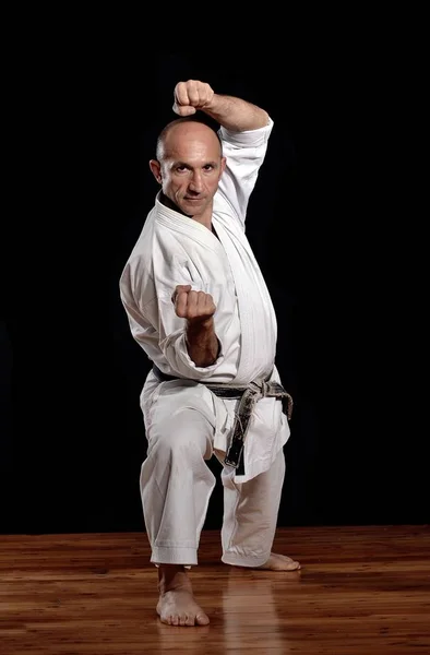Martial arts karate master training on black background.