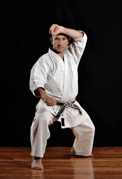 Martial arts karate master training on black background.