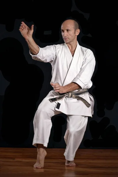 Martial arts karate master training on black background.