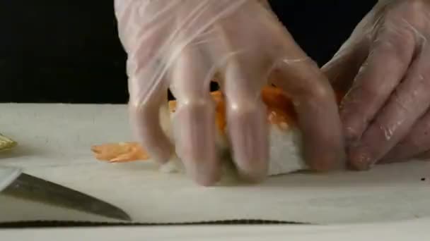 シェフがテーブルの上のレストランキッチンで鮭の巻き寿司を作る — ストック動画