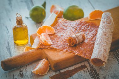 Mandarine pastila meyveleri ve küçük şişe gri ahşap masa üstünde a ahşap tahta üzerinde 