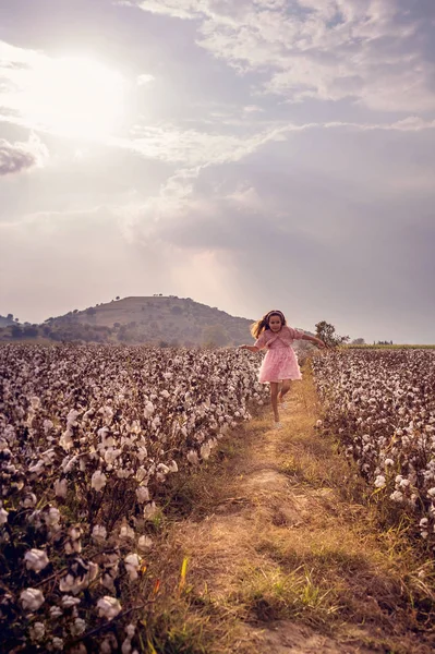 Güzel küçük kız uzun saçlı ve pembe elbiseli kız pamuk alanı atlama.