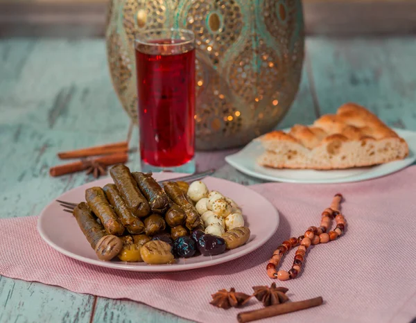 Turkish sarma on a plate with cheese, olives, pide, sorbet drink, rosary and seasonings on the table.  Photo with shallow depth of field