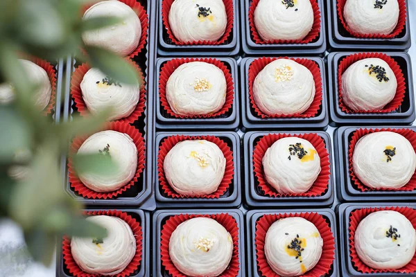 Chinese pastries are in a box with red paper below and black sesame on top