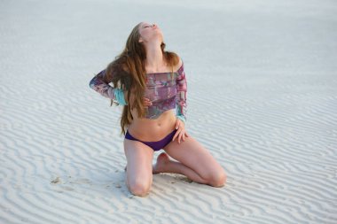 Tropik tatil gün batımında kumlu plajda poz uzun saçlı çarpıcı kızıl saçlı model