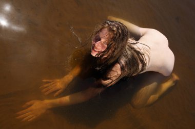 Kumlu plajda poz uzun saçlı genç kızıl saçlı model. Nehir sahilinde dinlenme sırasında çıplak kadın 