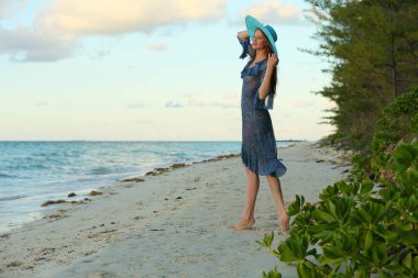 Tropik tatil gün batımında kumlu plajda poz uzun saçlı çarpıcı kızıl saçlı model