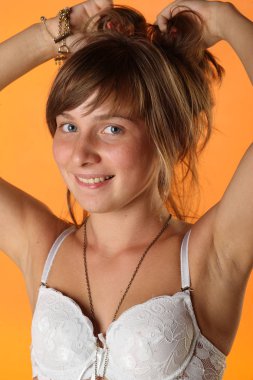 Turuncu stüdyo arka plan üzerinde çekici genç model soyunma. Güzellik kadının şık portresi 