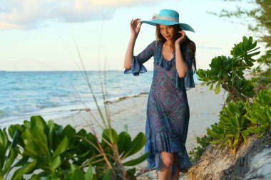 Tropik tatil gün batımında kumlu plajda poz uzun saçlı çarpıcı kızıl saçlı model