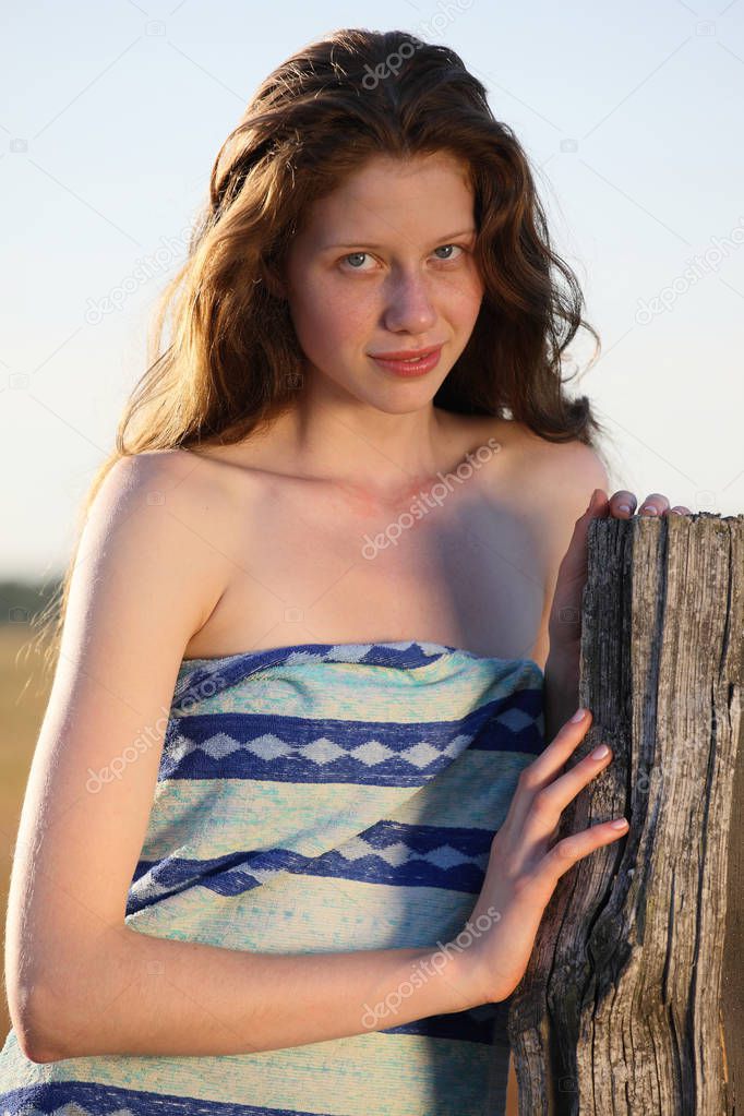 Outdoor portrait of beauty redhead model posing on nature background at daytime