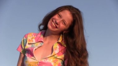 Deniz kıyısında poz verirken uzun saçlı, saçlarına dokunan güzel bir kadın.