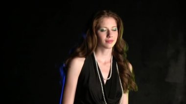 Siyah stüdyo geçmişinde poz veren güzel genç bir kadın.