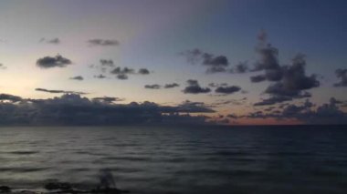 Gün doğumunda gökyüzünde bulutlar olan sonsuz dalgalı deniz yüzeyinin resimsel görüntüsü