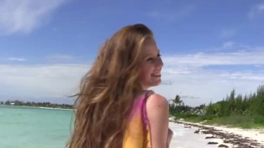 Uzun saçlı, bikinili ve güneşli bir günde deniz kıyısında poz veren çekici bir kadın.