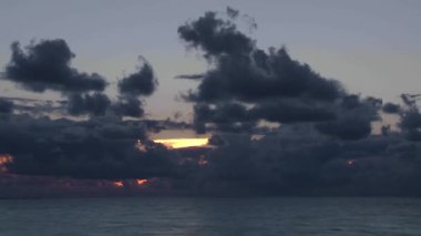 Gün doğumunda gökyüzünde bulutlar olan sonsuz dalgalı deniz yüzeyinin resimsel görüntüsü