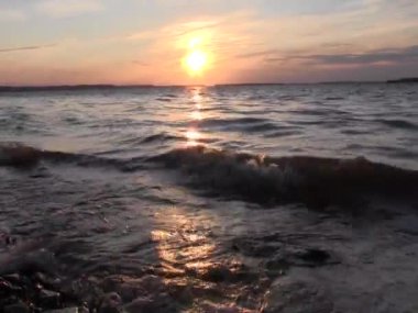 Sabahları dalgalı sahilde taşlarla güzel bir gün doğumu 