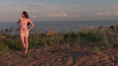 Deniz kıyısında poz veren uzun saçlı güzel bir kadın.