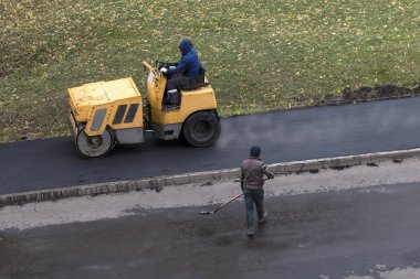 Yol inşaat işçisi taze sıcak asfalt kaldırımda presler silindir Kompaktör makine kullanıyor. Yol yenileme işlemi. Yüksek açılı görünüş.