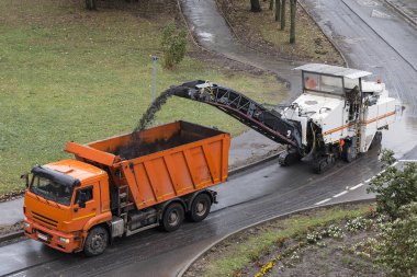 Yol freze makinesi eski asfalt kaldırır ve damperli kamyon öğütülmüş asfalt yükler. Yol inşaat çalışma. Yol onarım işlemi