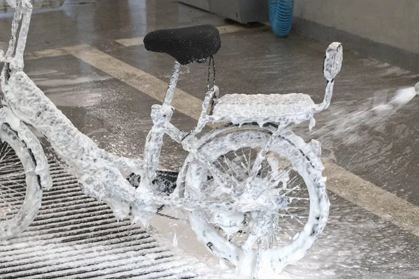 Elektrikli bisiklet araba yıkama köpük içinde. Bir bisiklet ile köpük bir jet yıkama.