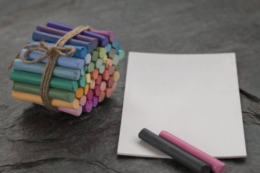 Koyu taş arka plan üzerinde beyaz suluboya kağıt ile renkli pastel boya kalemleri. Kopya alanı. Seçici odaklama