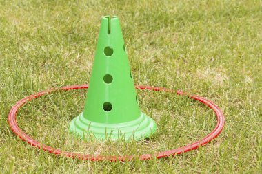 Parkta çim üzerinde kırmızı çember ile Yeşil plastik spor koni. Oynama zamanı, spor salonu zamanı. Çocuklar için açık hava oyunları oynamak için davet.