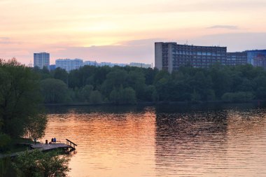 Nehir kıyısında insanlar şehir ve Park üzerinde etkileyici günbatımı hayran. Pembe ve Lila gün batımı ışığında güzel Clear