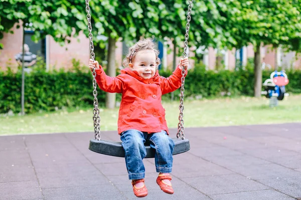 Ragazzina Trench Rosso Parco Giochi Bambino Altalena — Foto Stock