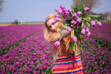 Uzun kızıl saçlı bir bouqu tutan çizgili bir elbise giyen kadın