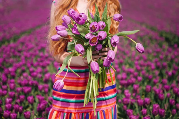 Woman with long red hair wearing a striped dress holding a bouqu — Stock Photo, Image