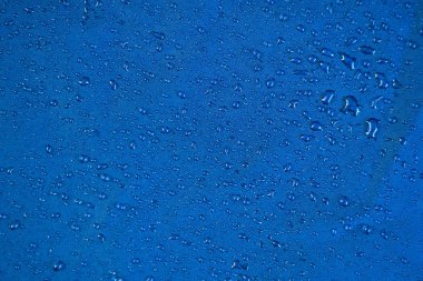 Görünüm doku mavi sentetik su geçirmez giyim. Su geçirmez naylon üzerine su damlaları. Suya dayanıklı tekstile yağmur damlaları. Yağmur damlası ile su geçirmez kaplama arka plan. Yağmur damlaları ile yağmur geçirmez çadır.