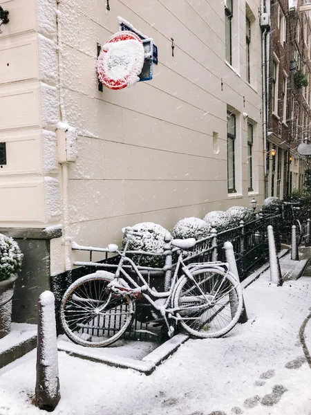 Snowy bicycles on the bridge in the city center from Amsterdam