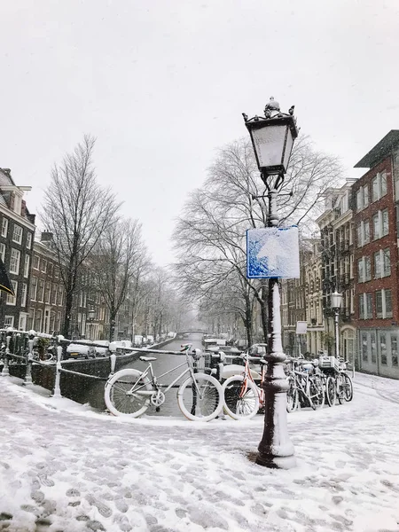 Snowy bicycles on the bridge in the city center from Amsterdam