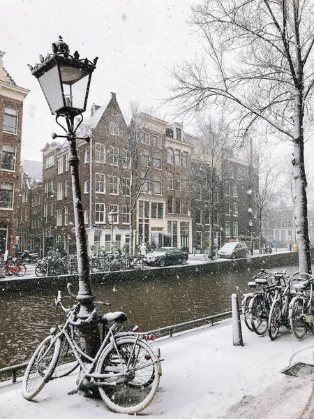 Snowy bicycles on the bridge in the city center from Amsterdam