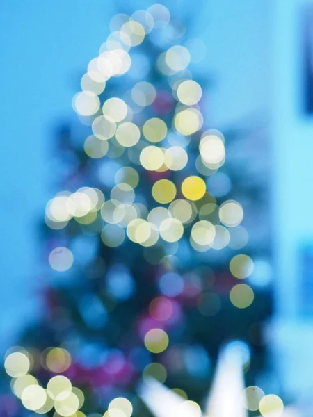 Christmas tree with defocused lights and star. Christmas abstract blur background. Out of focus holiday background with christmas tree. Light bokeh from Xmas tree. Xmas and New Year theme.