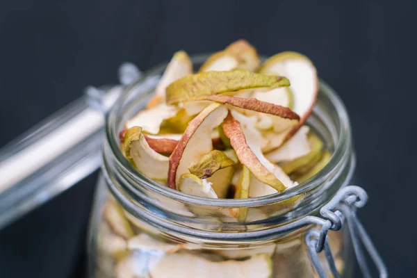 Homemade organic dried apple chips in glass bottle with fresh ap