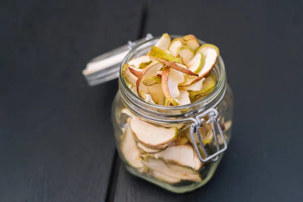 Homemade organic dried apple chips in glass bottle with fresh apple chips