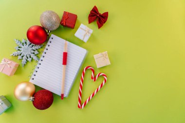 Noel dilek listesi tebrik kartı. Noel kompozisyonu. Mevcut kutu, ilk ağaç dalları, Xmas şekerlemeleri, yeşil arka planda kırmızı şenlik süsleri. Uzayı kopyala Noel ve yeni yıl tatili konsepti