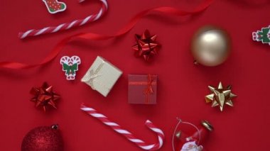 Noel arkaplanı. 4k Döndürme Videosu hediye kutusu, köknar ağacı dalları ve birçok Xmas çizgili şeker, kırmızı arka planda kırmızı şenlik süslemeleri. Noel ve yeni yıl tatili konsepti